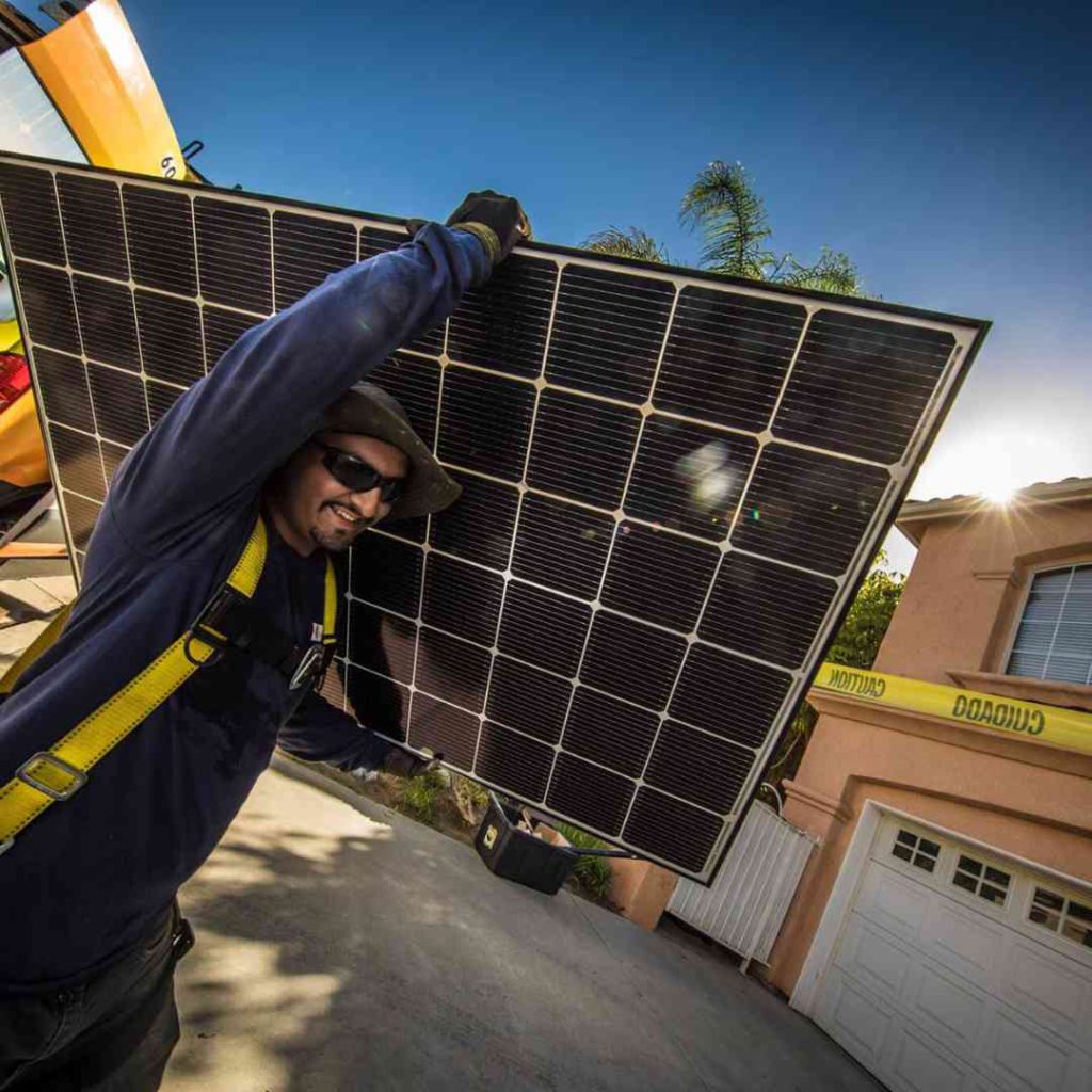 Photo of LASG installer carrying a solar panel